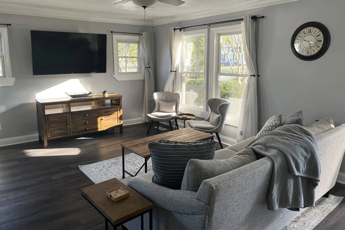 A cozy living area with a plush sofa, coffee table, television, and ample windows letting in natural light. The space is arranged for relaxation, family game nights, or watching your favorite shows after a day of adventure.